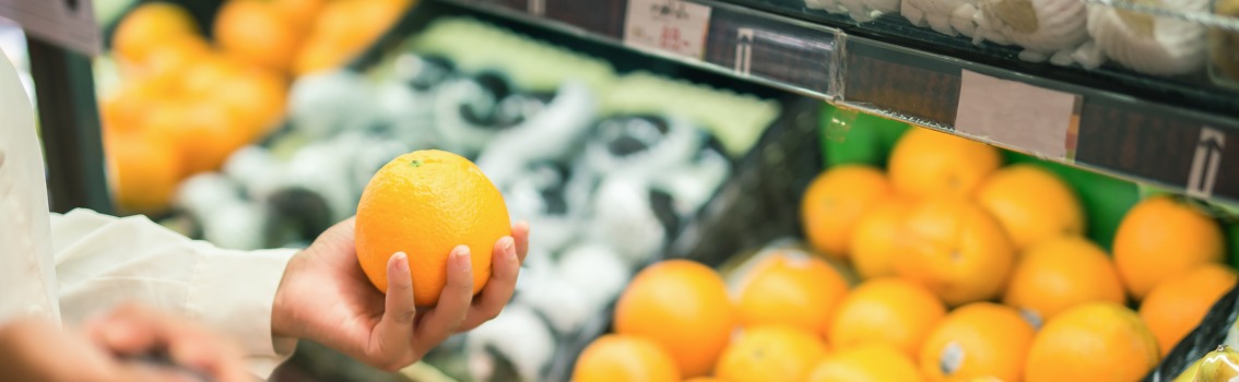 Mujer en el supermercado con naranjas en la mano
